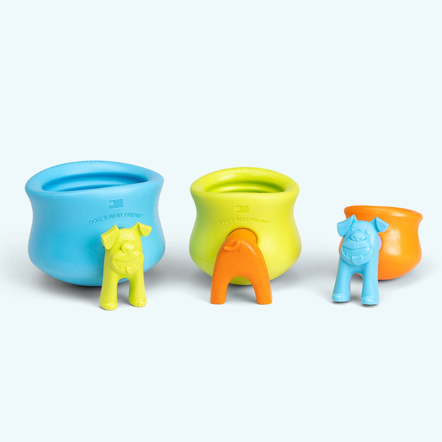 A lineup of a blue, a lime green and an orange rubber work-to-eat dog toy ain size order, each with it's opening plugged by a dog-shaped toy stopper