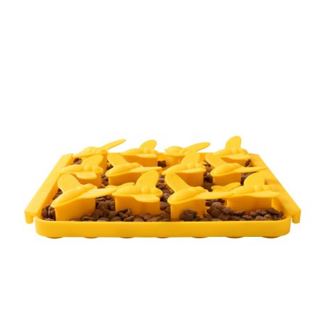 A dog work-to-eat lick mat with yellow raised bumblebee-shaped surface filled with kibble