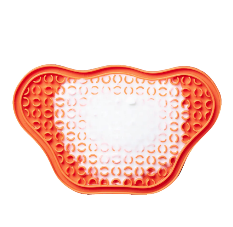 an orange feeding lick mat for dogs, smeared with yogurt