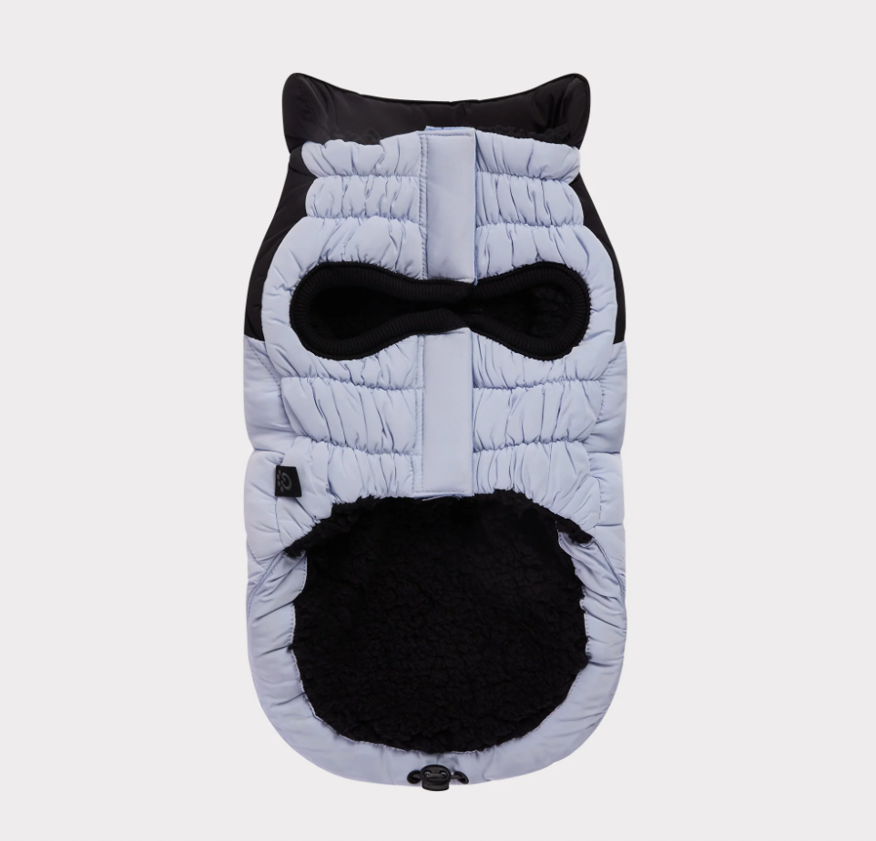 The underside of a quilted dog coat with a black fleece lining