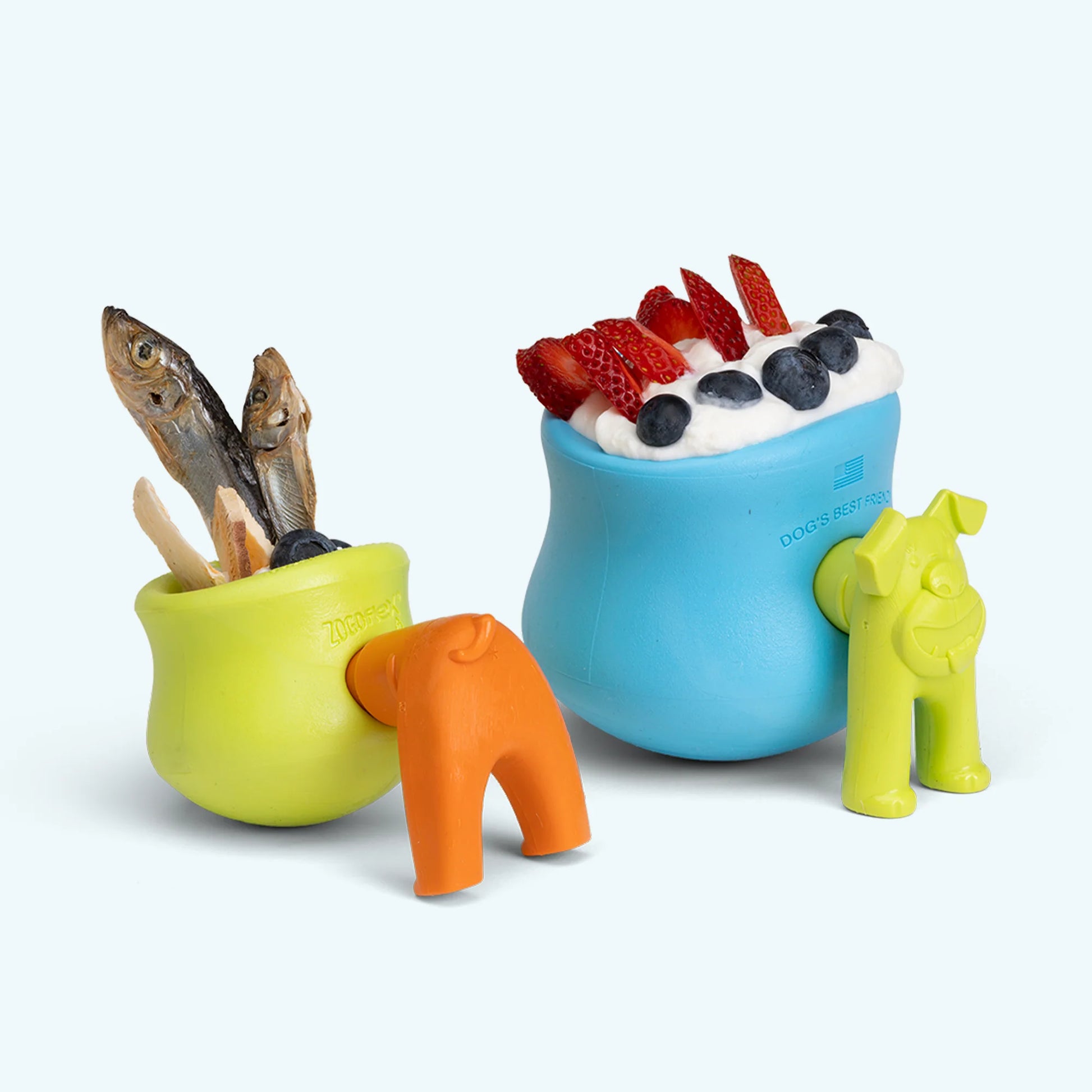 A lime green rubber work-to-eat dog toy and a blue rubber work-to-eat toy, both filled with various delicious foods, with toy stoppers shaped like dog butt and dog face 