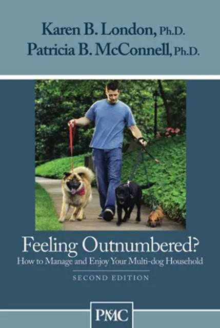 A blue dog training book called Feeling Outnumbered, featuring a photo of a person walking 2 dogs in a park
