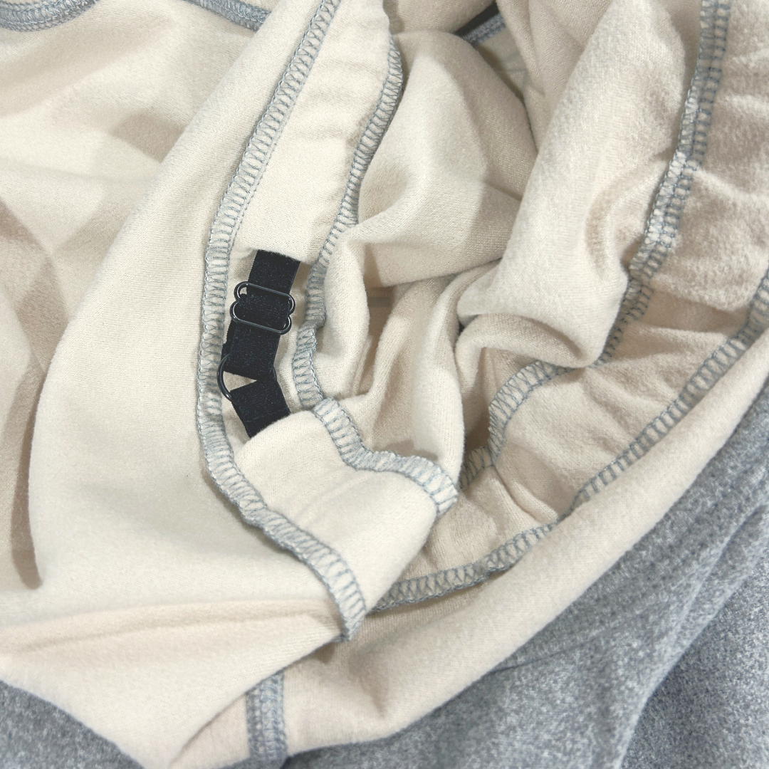 Closeup of the interior adjustment strap of a heathered grey onesie for dogs